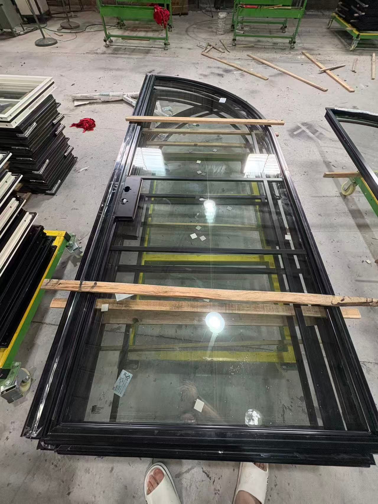 Custom arched door frame and glazing unit on factory floor during production